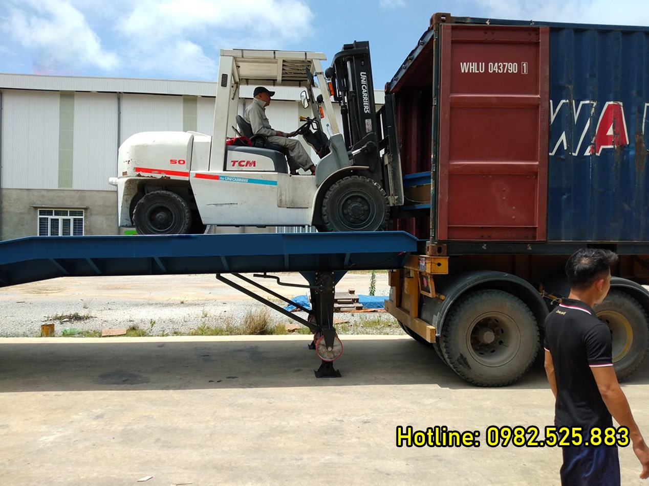 Trong ảnh có 2 người đang làm việc, 1 chiếc xe nâng màu trắng.